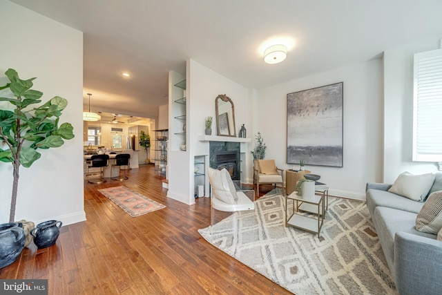 living room featuring hardwood / wood-style flooring, ceiling fan, and a fireplace