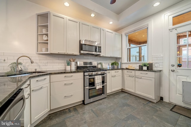 kitchen featuring dark stone countertops, white cabinetry, appliances with stainless steel finishes, and sink