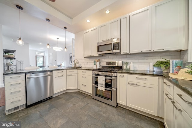 kitchen featuring stainless steel appliances, backsplash, hanging light fixtures, white cabinets, and dark stone countertops