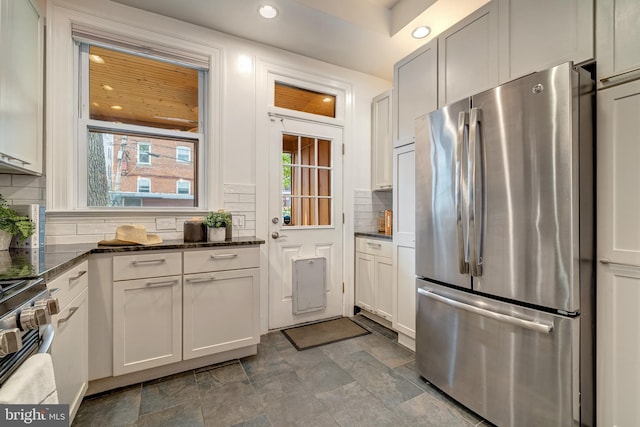 kitchen with dark stone counters, backsplash, white cabinets, and stainless steel appliances