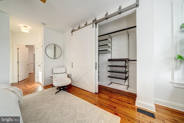 bedroom with light hardwood / wood-style flooring, a barn door, and a closet