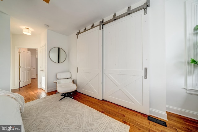 unfurnished bedroom featuring a barn door and light hardwood / wood-style flooring