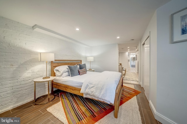 bedroom with brick wall and hardwood / wood-style flooring