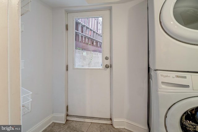 laundry area featuring light tile patterned flooring and stacked washer / drying machine