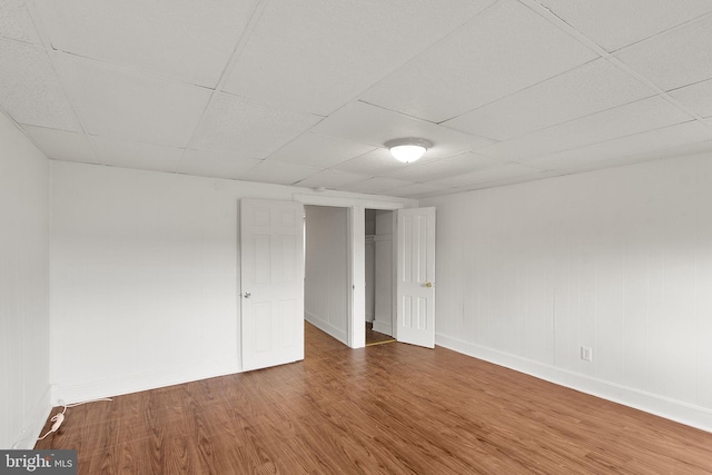 unfurnished bedroom with wood-type flooring and a drop ceiling