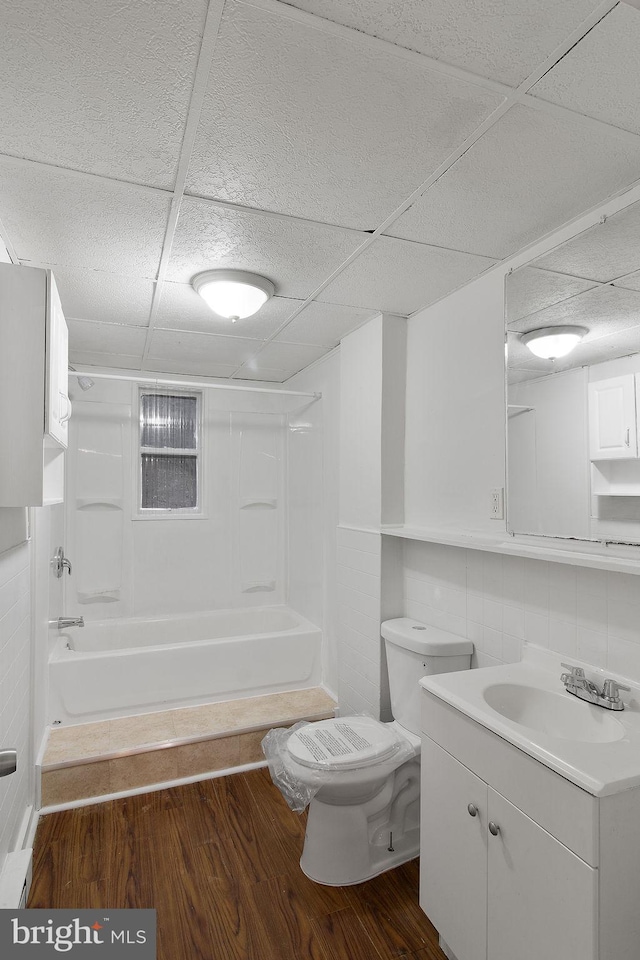 full bathroom with toilet, a paneled ceiling, and wood-type flooring