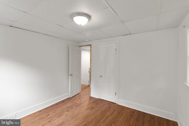 unfurnished room with a drop ceiling and hardwood / wood-style flooring