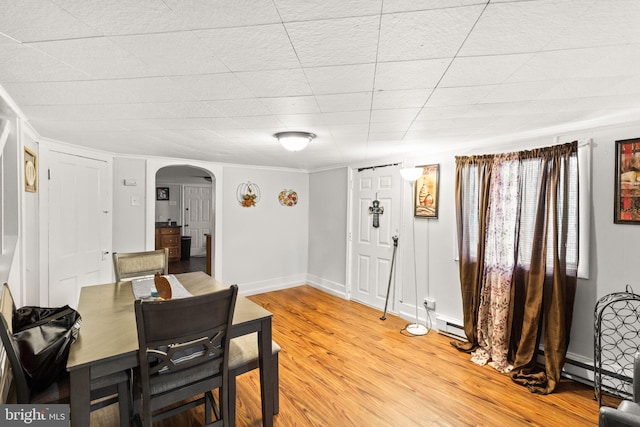 dining area with ornamental molding, a baseboard heating unit, and light hardwood / wood-style flooring