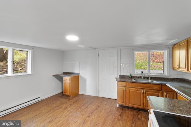 kitchen featuring light hardwood / wood-style floors, baseboard heating, sink, and tasteful backsplash