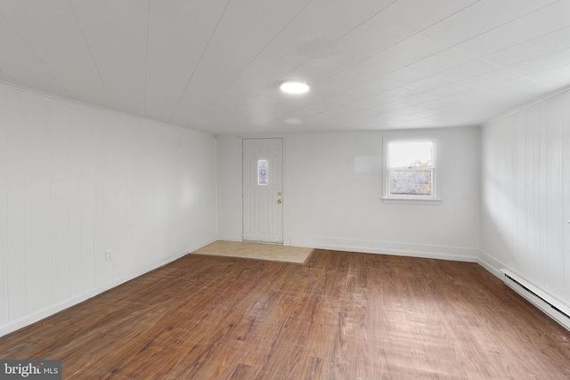 interior space with wood-type flooring, crown molding, and a baseboard heating unit