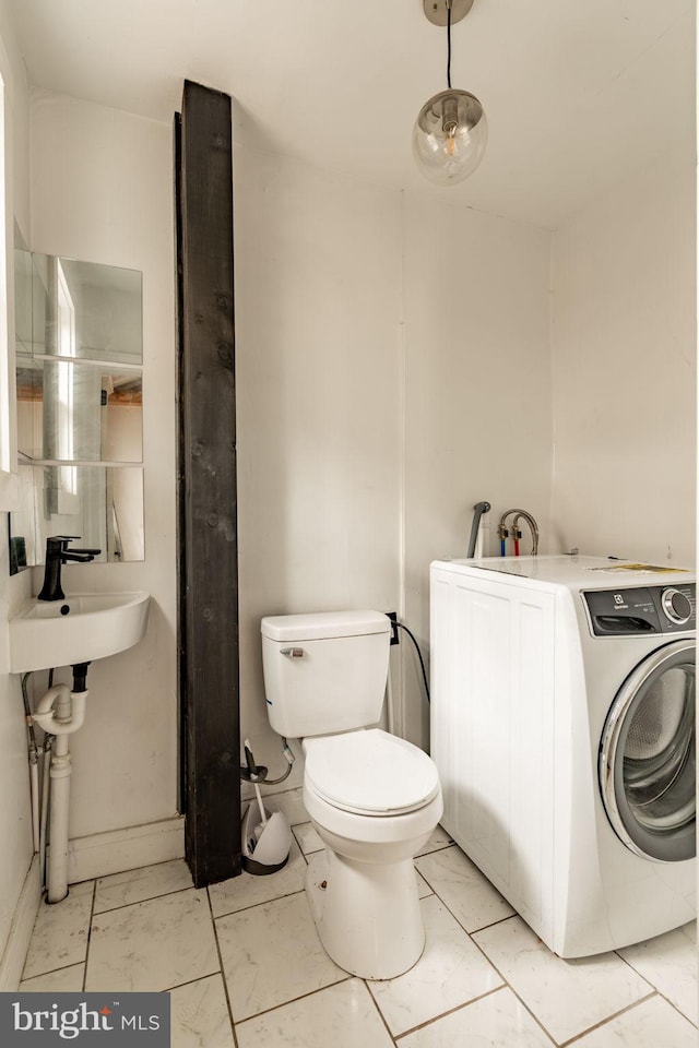 bathroom featuring toilet, washer / dryer, and sink