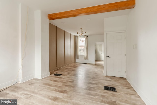 spare room featuring beamed ceiling, a chandelier, and light wood-type flooring