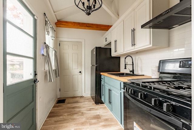 kitchen featuring black appliances, wall chimney range hood, white cabinetry, a healthy amount of sunlight, and butcher block counters