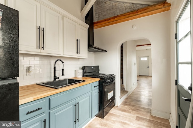 kitchen featuring tasteful backsplash, black appliances, light hardwood / wood-style flooring, white cabinets, and butcher block countertops