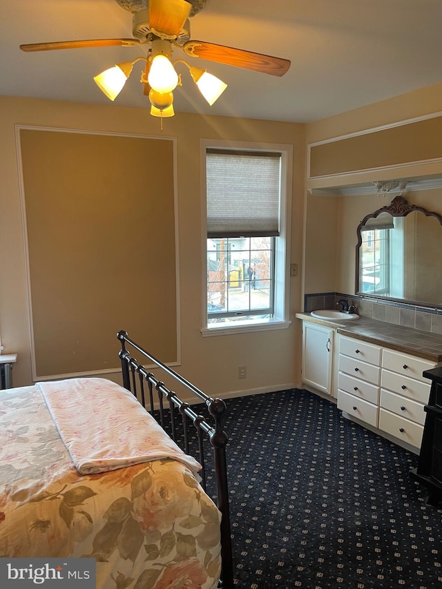 bedroom with multiple windows, ceiling fan, sink, and dark colored carpet