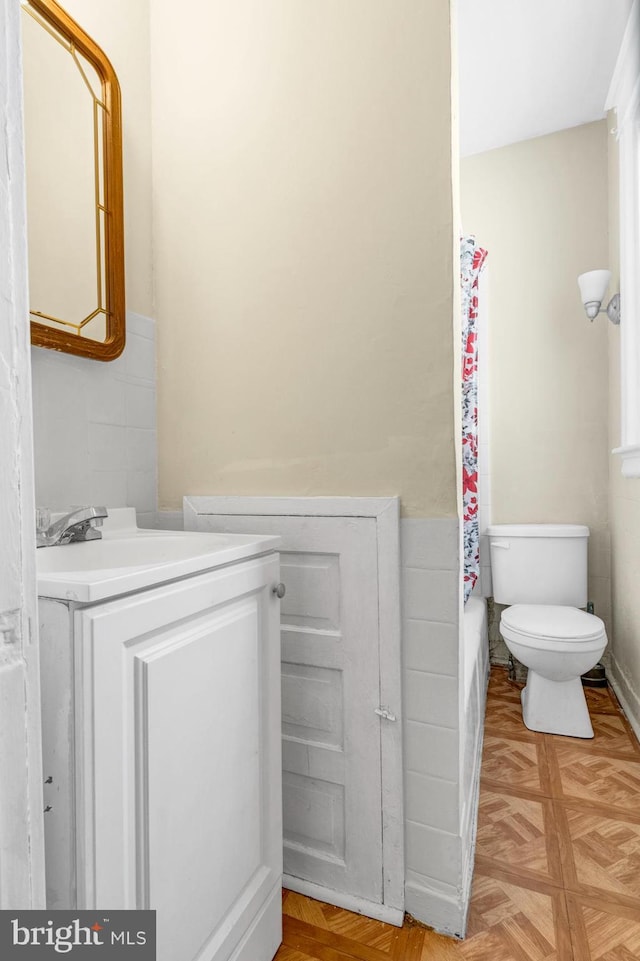 bathroom featuring parquet flooring, vanity, and toilet