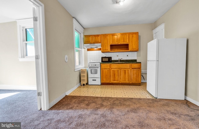 kitchen with backsplash, white appliances, sink, and light carpet