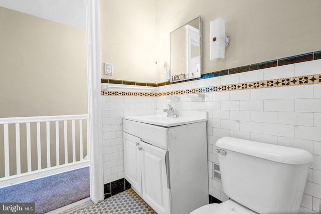 bathroom featuring vanity, toilet, and tile walls