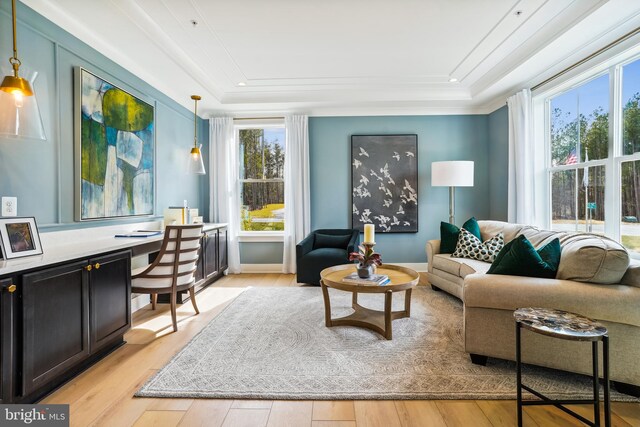 living room featuring built in desk, a raised ceiling, light hardwood / wood-style flooring, and ornamental molding