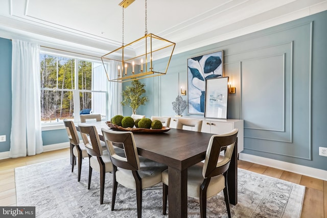 dining space featuring light hardwood / wood-style floors, a chandelier, and ornamental molding