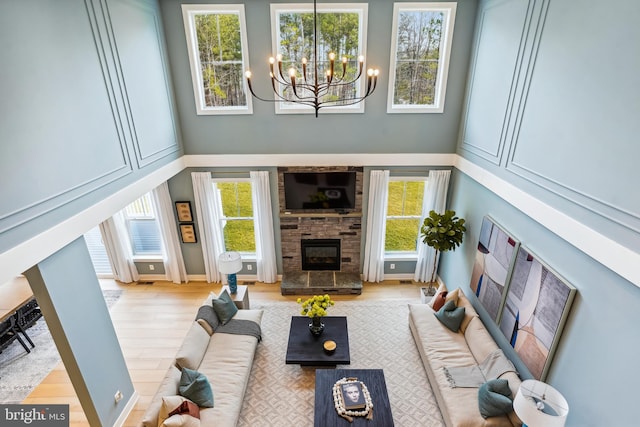 living room with a stone fireplace, a chandelier, and a healthy amount of sunlight