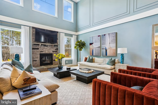 carpeted living room featuring a fireplace, a high ceiling, and plenty of natural light