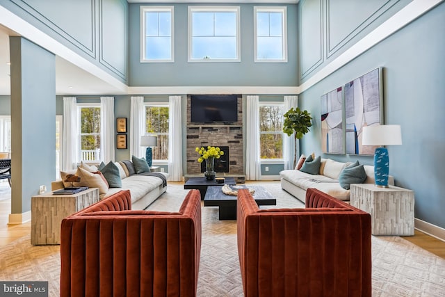 living room featuring a towering ceiling, a fireplace, and light wood-type flooring