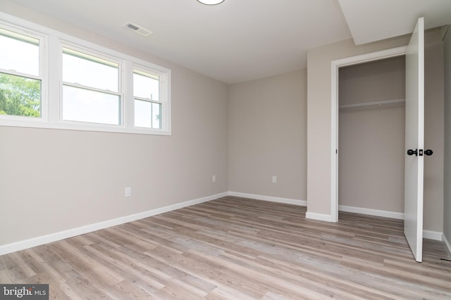 unfurnished bedroom with light hardwood / wood-style flooring and a closet