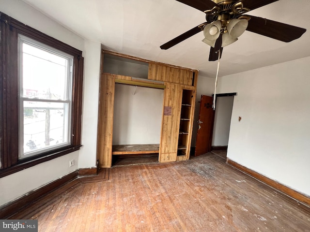 unfurnished bedroom featuring dark hardwood / wood-style floors, ceiling fan, multiple windows, and a closet