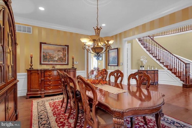 dining space with wood-type flooring, crown molding, and a notable chandelier