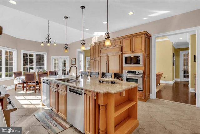 kitchen featuring built in appliances, light stone countertops, pendant lighting, sink, and a kitchen island with sink