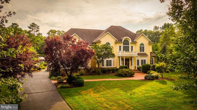 view of front of home featuring a lawn and a balcony