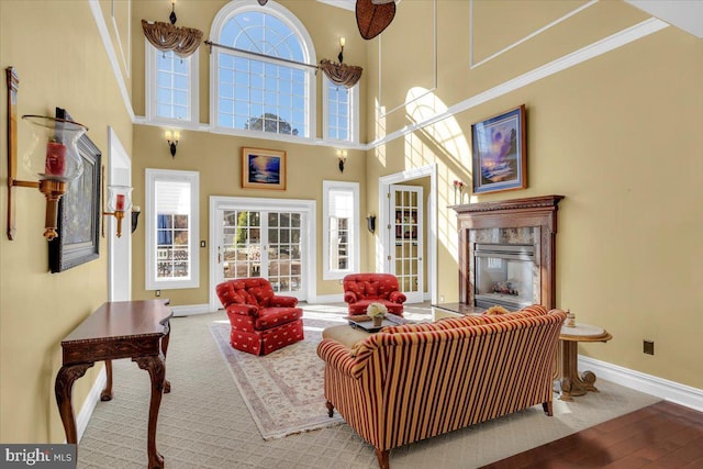 living room featuring hardwood / wood-style floors, a high end fireplace, ornamental molding, and a towering ceiling