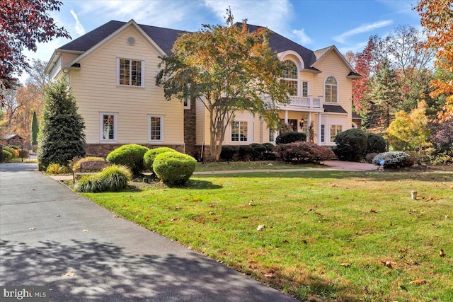 view of property featuring a front lawn and a balcony