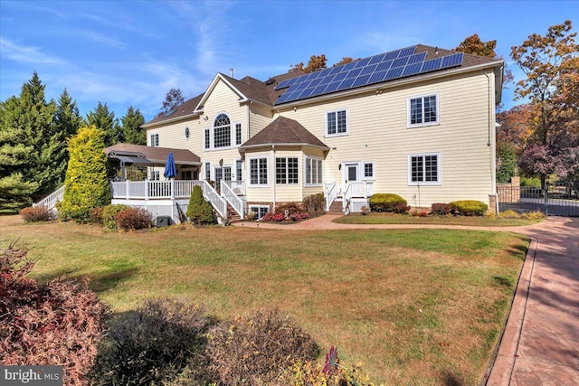 rear view of property featuring a deck and a lawn