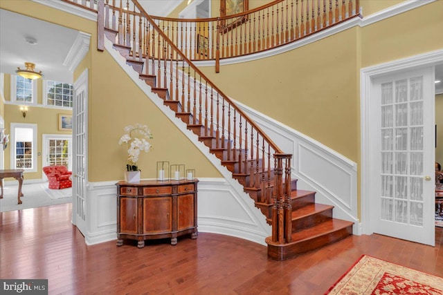 stairs featuring a high ceiling, hardwood / wood-style floors, and crown molding