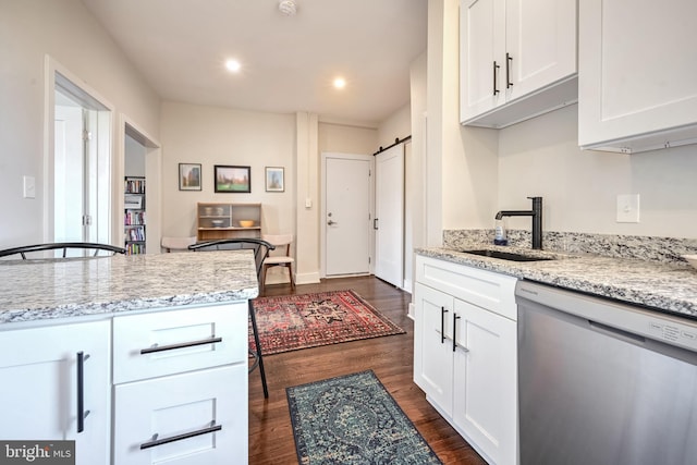 kitchen with a barn door, white cabinetry, dishwasher, and light stone counters