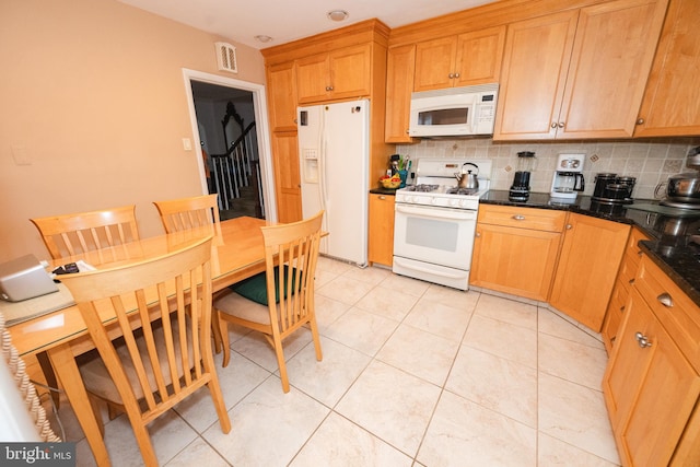 kitchen with dark stone counters, tasteful backsplash, white appliances, and light tile patterned flooring