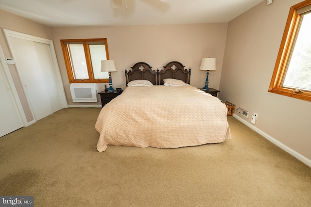 bedroom with a wall mounted AC, light colored carpet, and ceiling fan