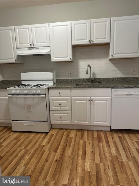 kitchen with sink, white appliances, white cabinets, light wood-type flooring, and decorative backsplash