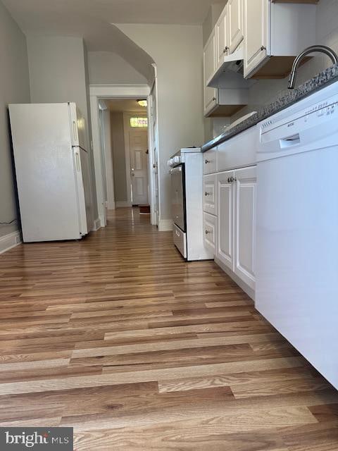 kitchen with white cabinets, white appliances, sink, and light hardwood / wood-style flooring