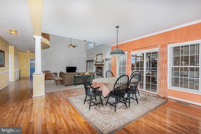 dining room with decorative columns, ceiling fan, crown molding, and light wood-type flooring