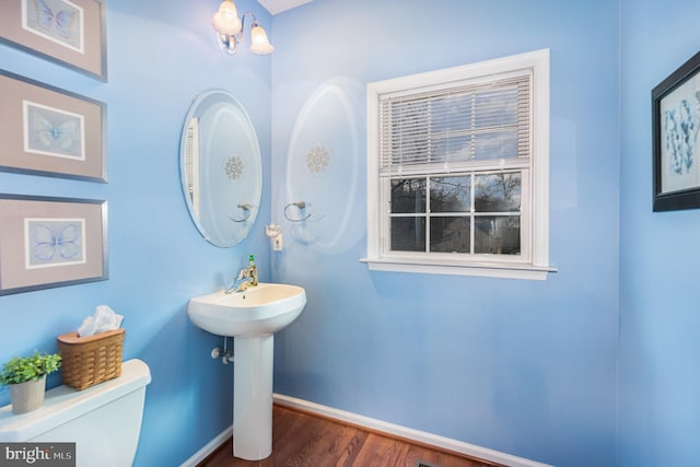 bathroom with wood-type flooring, toilet, and sink