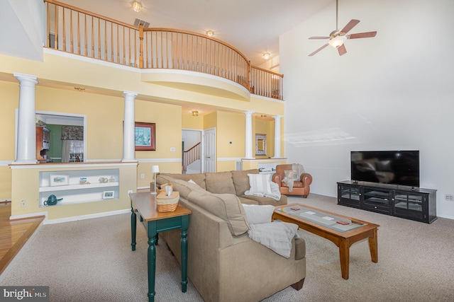 living room featuring carpet flooring, ornate columns, and a high ceiling