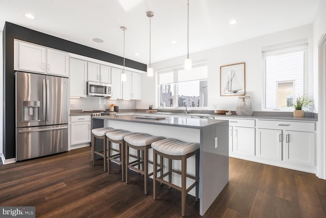 kitchen with stainless steel appliances, white cabinetry, and dark wood-type flooring