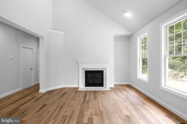 unfurnished living room with high vaulted ceiling and light hardwood / wood-style flooring