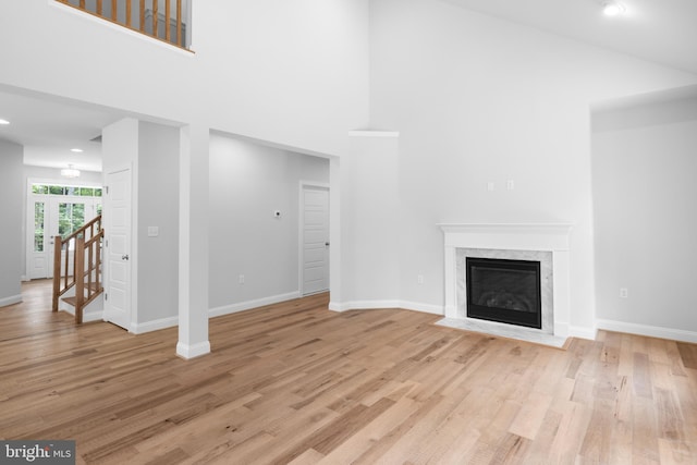 unfurnished living room with a fireplace, a high ceiling, and light wood-type flooring