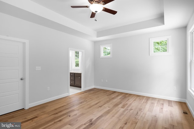 spare room featuring light hardwood / wood-style floors, ceiling fan, and a tray ceiling