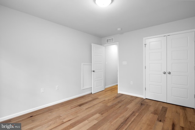 unfurnished bedroom with light hardwood / wood-style flooring and a closet