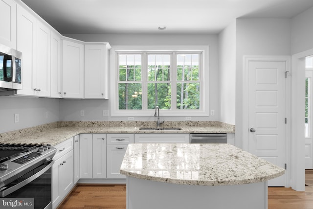 kitchen featuring appliances with stainless steel finishes, light hardwood / wood-style floors, white cabinetry, and sink